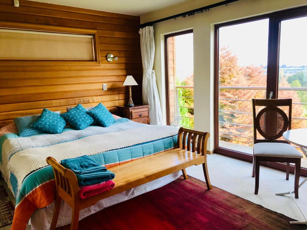 1 dormitorio con cama con banco y ventana en Suite abierta todo el año con vistas al campo, lago y ciudad, en Puerto Varas