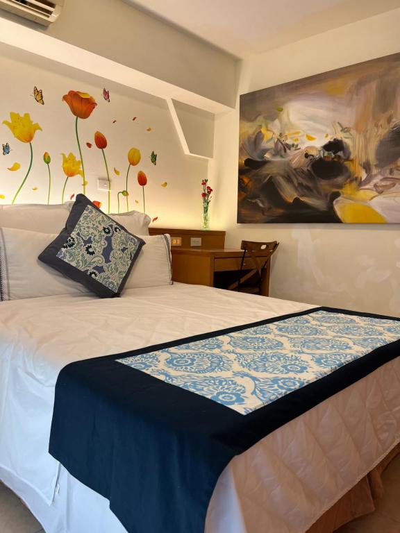 a bedroom with a bed with a painting on the wall at Tainan Canal Guest House in Anping