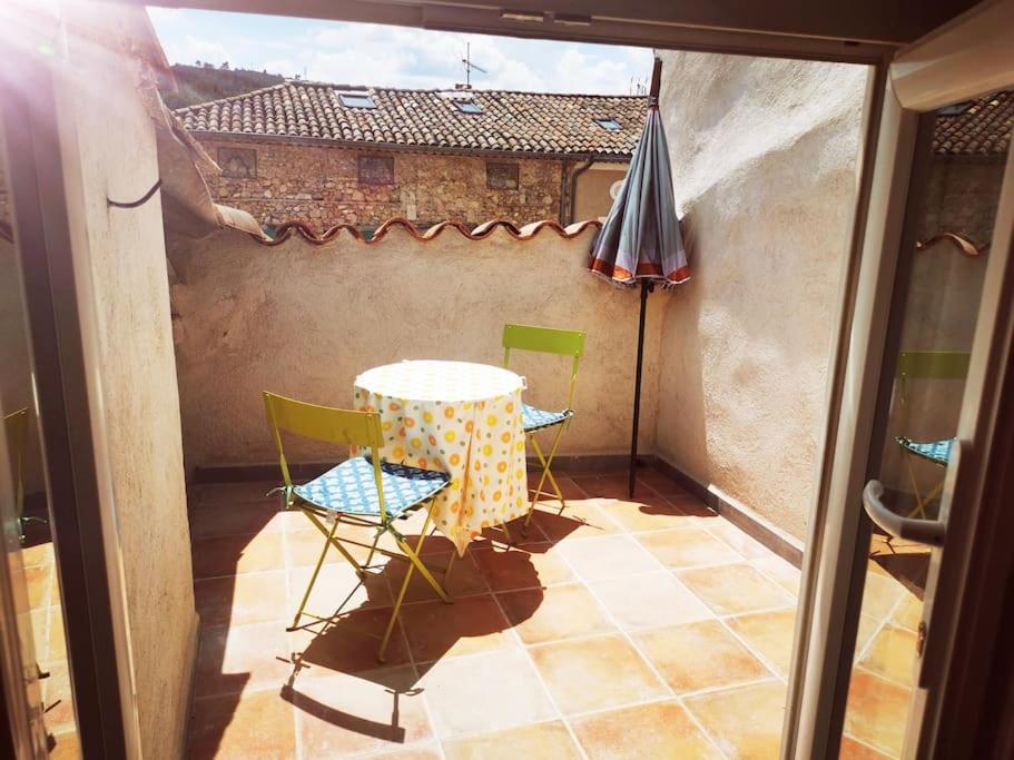 a patio with a table and chairs and an umbrella at Appartement avec terrasse in Saint-Martin-de-Brômes