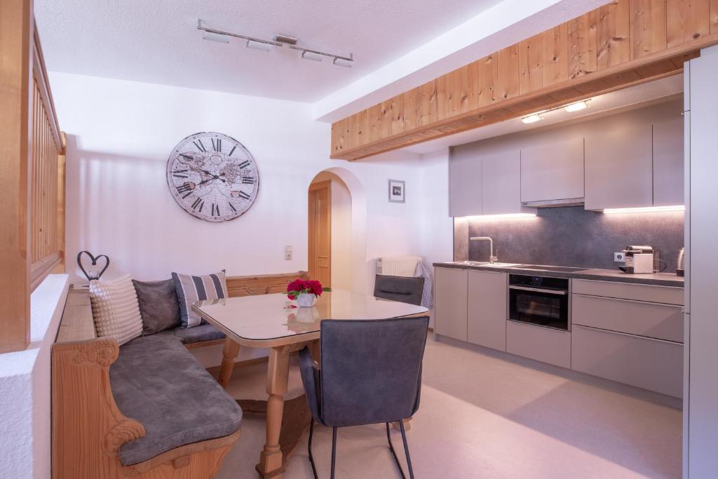 eine Küche und ein Wohnzimmer mit einem Tisch und einer Uhr in der Unterkunft Haus Praxmarer in Sankt Anton am Arlberg