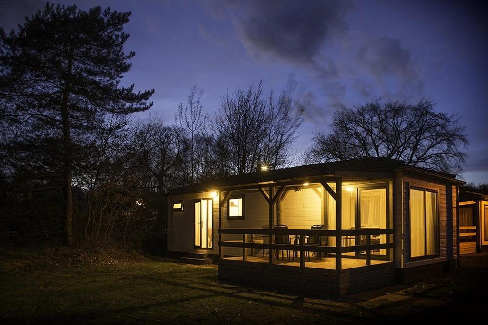 a small cabin with lights on at night at Recreatiepark Maas en Bos in Wellerlooi