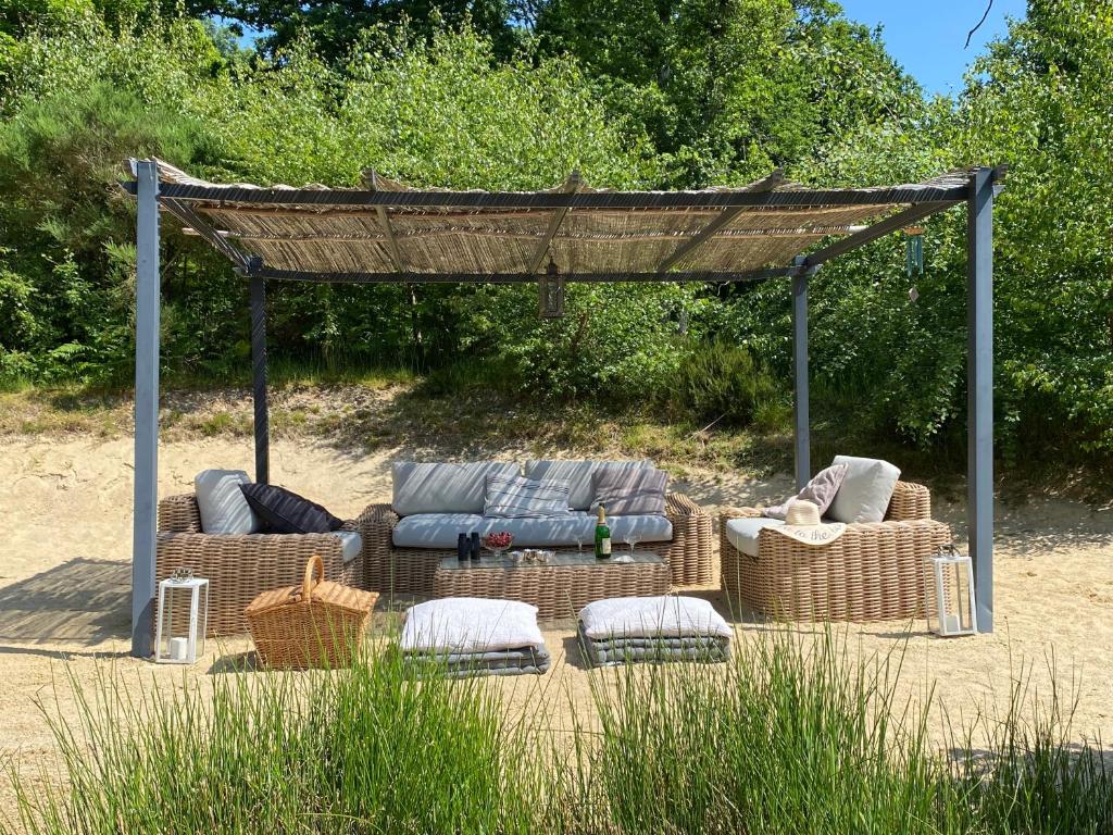 a gazebo with couches and chairs in the sand at 'Hotel One Suite' Suite with Private Beach, Natural Swimming Pool & Reserve in Neung-sur-Beuvron