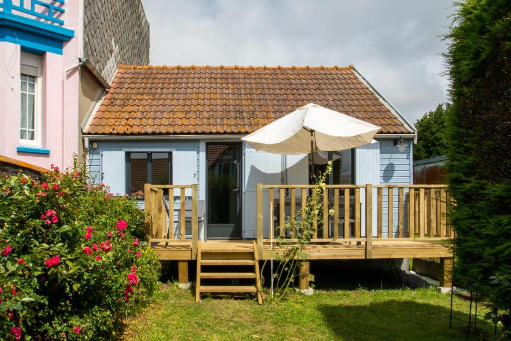 une terrasse en bois avec un parasol et une maison dans l'établissement La Maison Bleue avec Jardin à Mers-Les-Bains, à Mers-les-Bains