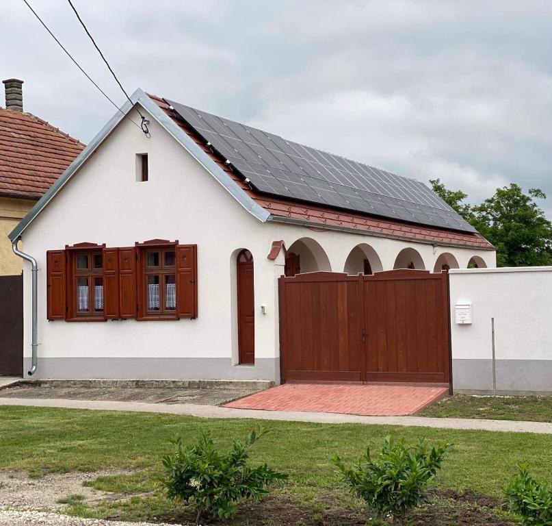 una casa bianca con un cancello in legno e una recinzione di SZÍVES LAK 