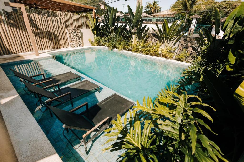 een zwembad met twee stoelen en een tafel en sidx sidx sidx bij Pousada Zama in Camburi