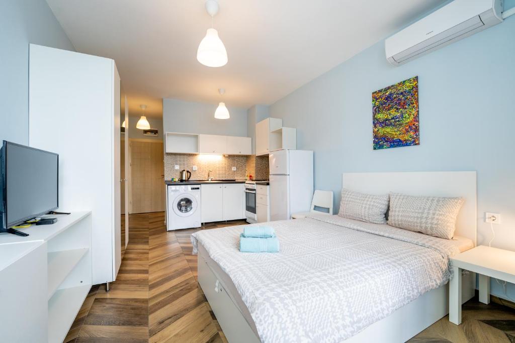 a white bedroom with a bed and a kitchen at Cozy little apartment in Studentski grad in Sofia