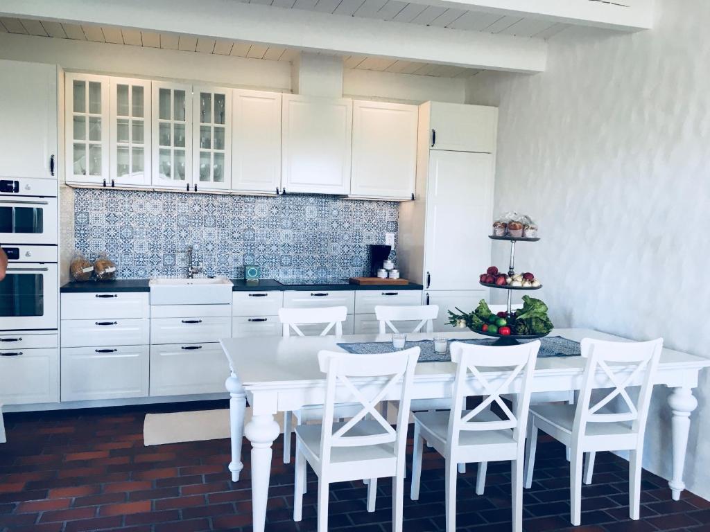 a white kitchen with a white table and white chairs at Västergård in Höganäs