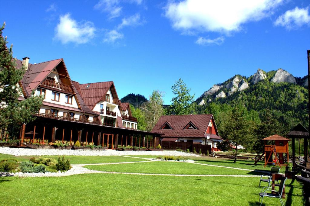 a large building with mountains in the background at Hotel Nad Przełomem in Sromowce Niżne