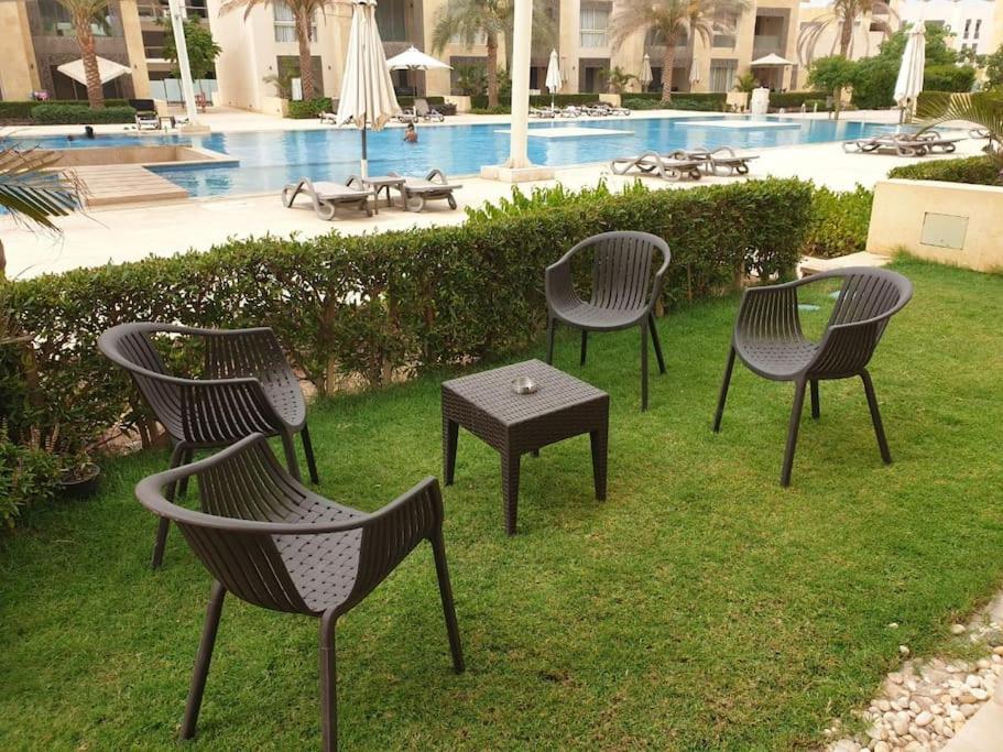 - un groupe de chaises et une table à côté de la piscine dans l'établissement Mangroovy - Delicate 1BR Ground floor by the Pool, à Hurghada