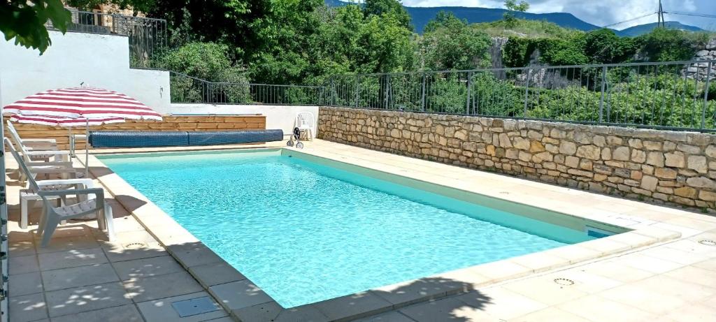 - une piscine avec une chaise et un parasol dans l'établissement Gîte confortable village médiéval Sainte-Jalle Baronnies provençales, à Sainte-Jalle
