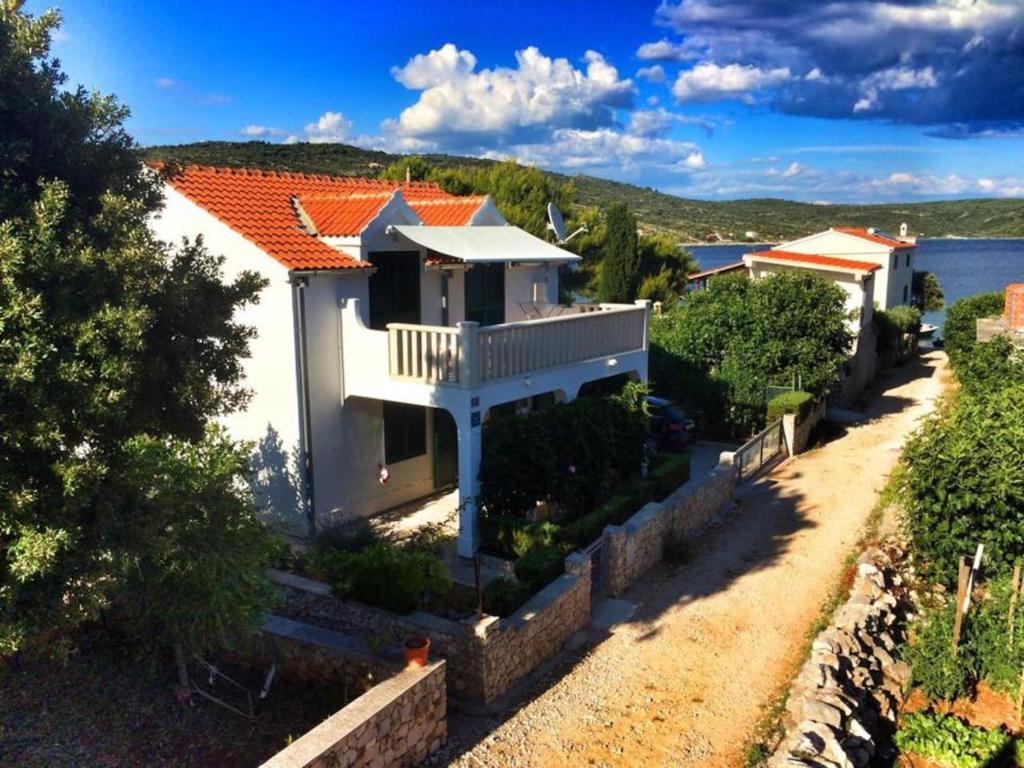 a white house with an orange roof and a road at Apartman Marla in Sevid