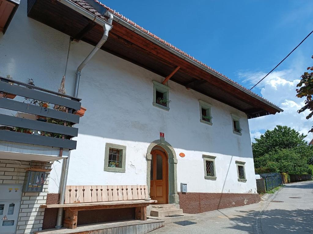 uma casa branca com uma porta de madeira e um banco em Pr Močnk em Bled