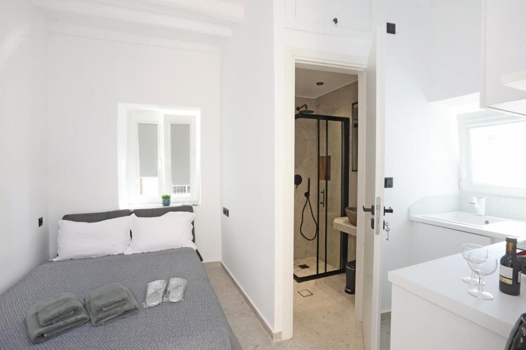 ein weißes Bad mit einem Bett und einem Waschbecken in der Unterkunft Cozy By Syros Bnb in Ermoupoli