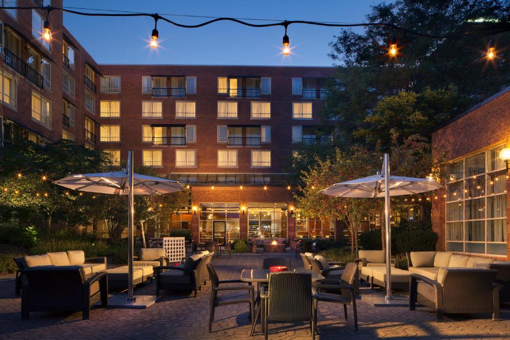 a patio with tables and umbrellas in front of a building at The Westin Princeton at Forrestal Village in Princeton