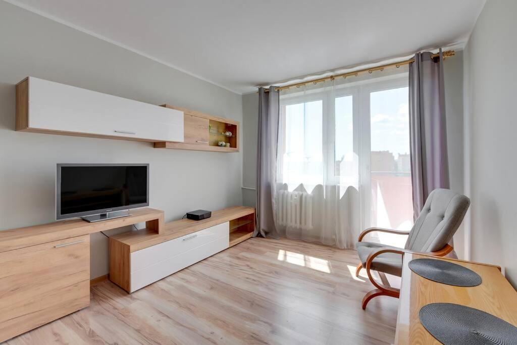 a living room with a television and a table with a chair at Motława 2 by Grand Apartments in Gdańsk