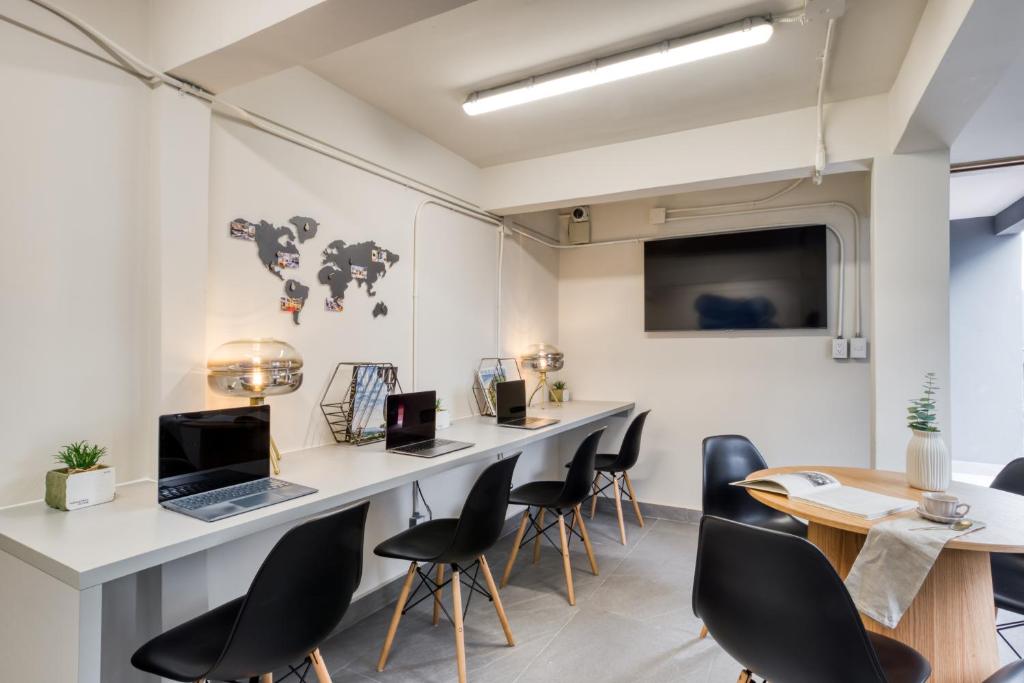 A shared workroom offers individual desks, laptops, and a small meeting table.