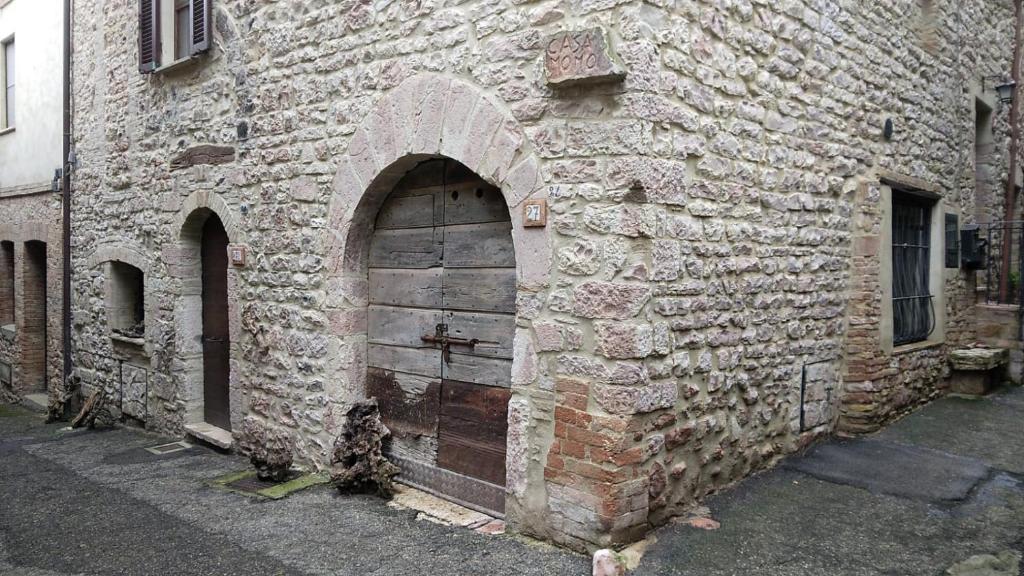 ein altes Backsteingebäude mit einer Holztür in der Unterkunft Casa Momo in Montecchio