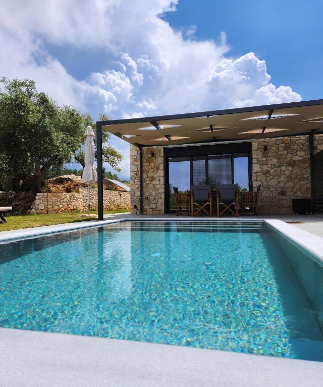 a swimming pool in front of a house at Elaionas Estate Perdika in Perdika