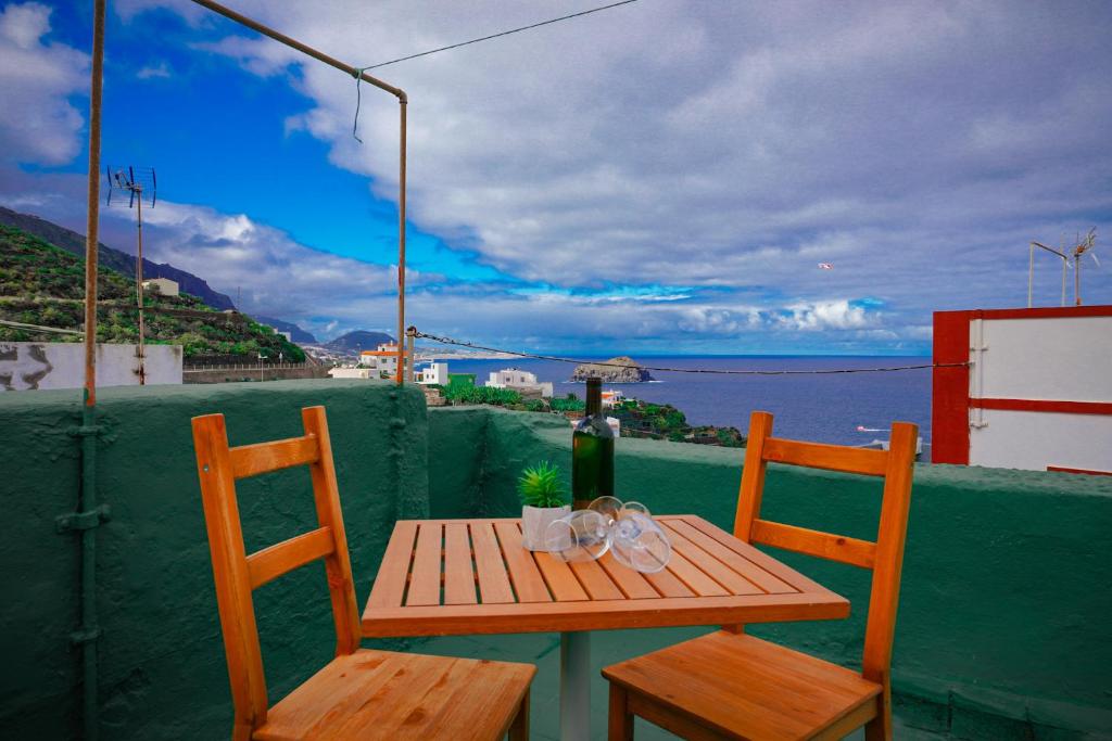 una mesa de madera y sillas en un balcón con vistas al océano en Casa El Guincho, Garachico en El Guincho