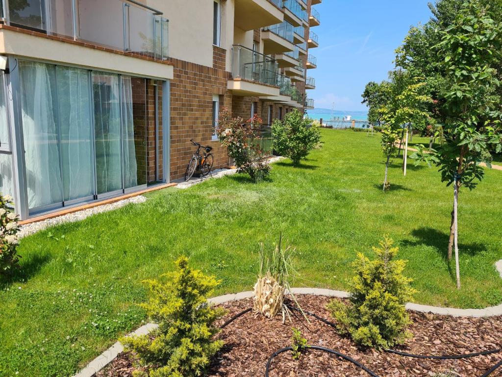 a yard of a building with grass and plants at EDA Beach Galerius Apartman in Siófok