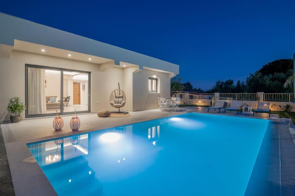 a villa with a swimming pool at night at Villa Adiola, An Unrivalled Retreat in Kalamaki