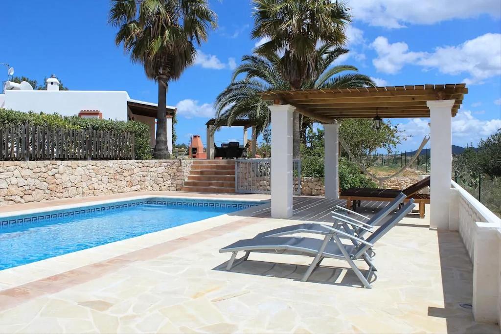 a chair under a pergola next to a swimming pool at Villa Can Portmany in Sant Josep de sa Talaia