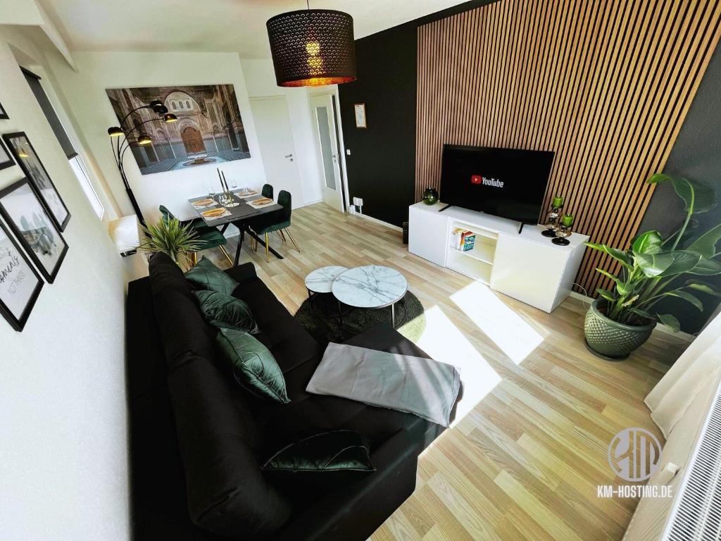 uma sala de estar com um sofá preto e uma mesa em KMHosting Luxe Apartment Chemnitz-Zentrum em Chemnitz