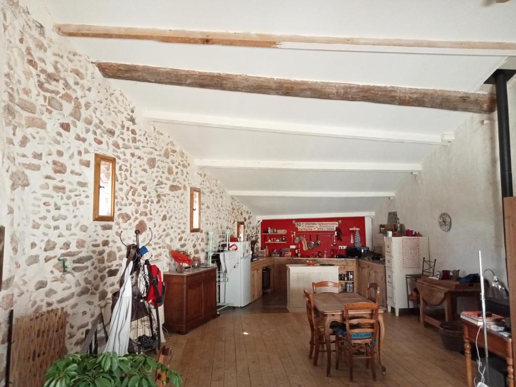 une cuisine et une salle à manger avec un mur en pierre dans l'établissement Maison de village 100m2, à Bédoin