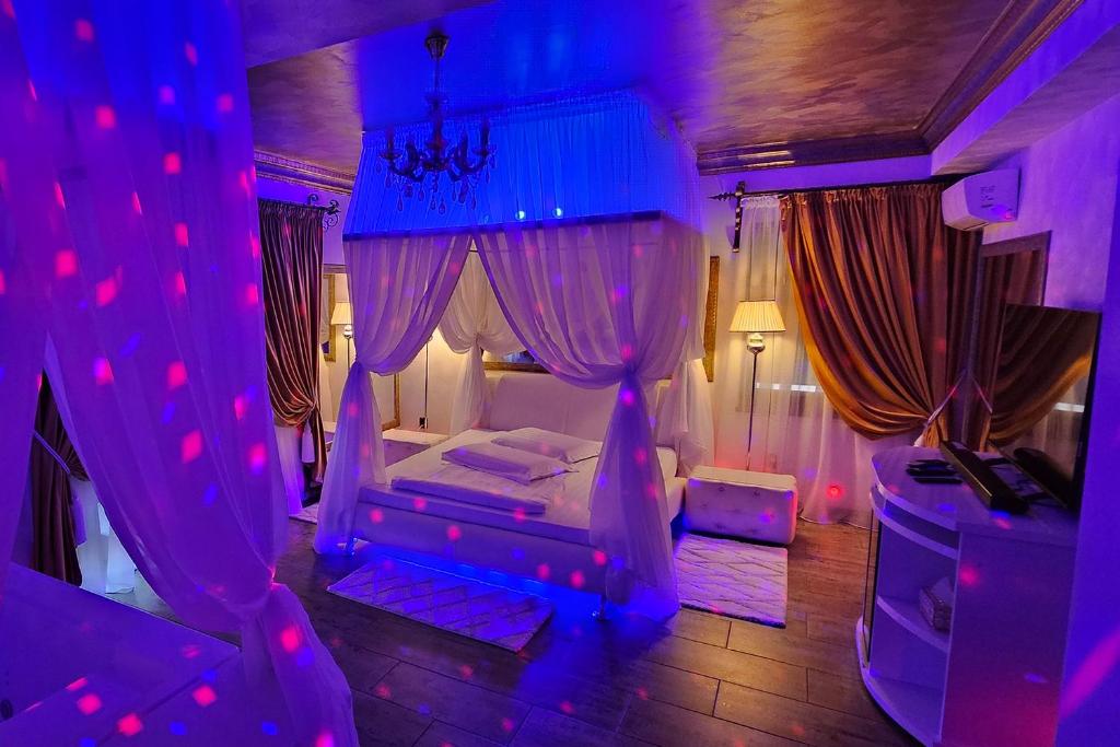 een slaapkamer met een bed met paarse verlichting bij Hotel Boutique Mikaela (Adult Only) in Braşov