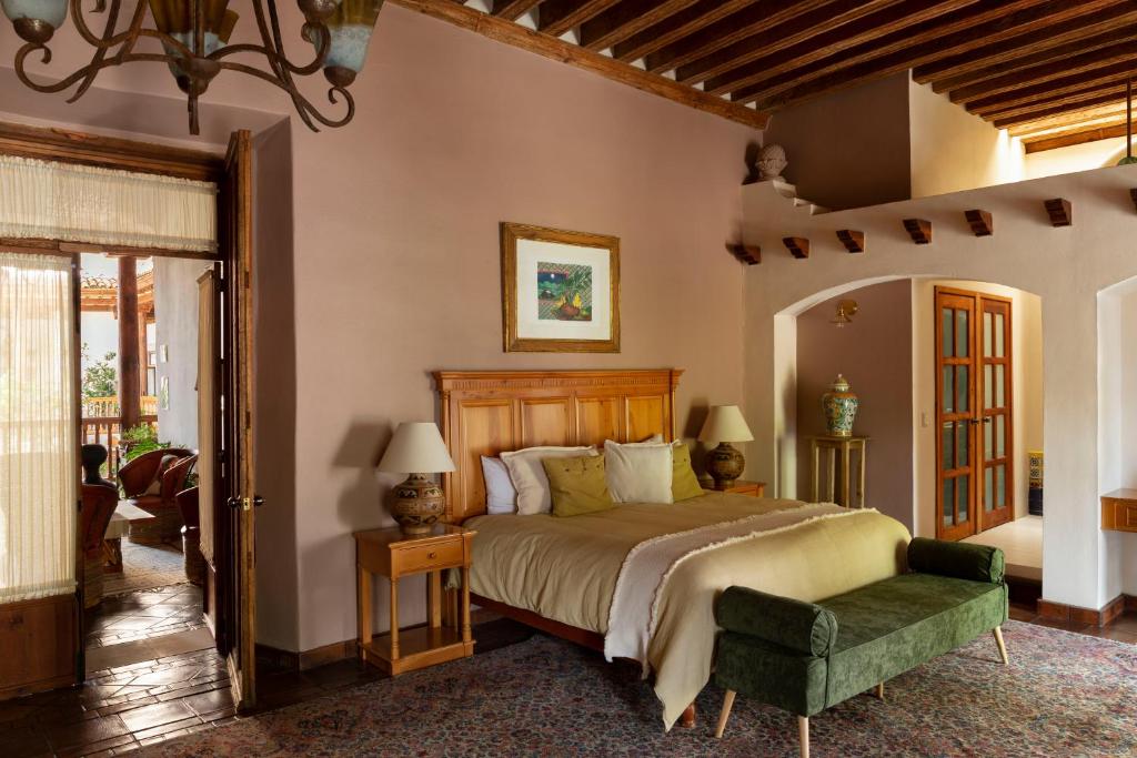 - une chambre avec un grand lit et une chaise verte dans l'établissement Hotel Casa del Naranjo, à Pátzcuaro