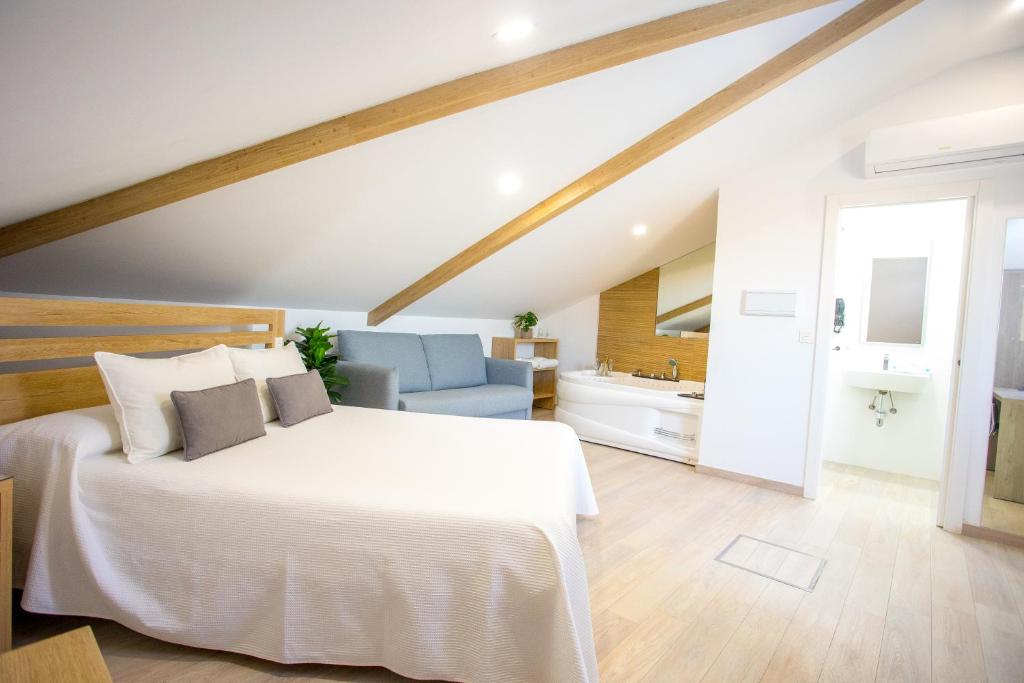 1 dormitorio con 1 cama blanca y 1 sofá azul en Apartahotel Énfasis-Group en El Cuervo
