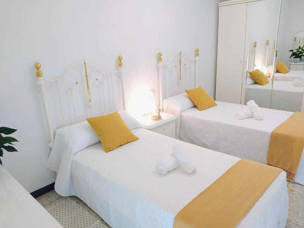 a bedroom with two beds with yellow and white at Alojamiento Caldas Centro in Caldas de Reis