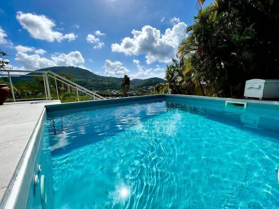 - une piscine bleue avec vue sur les montagnes dans l'établissement Villa Dezil - Villa de Standing 6/8 pers - Piscine, à Les Trois-Îlets