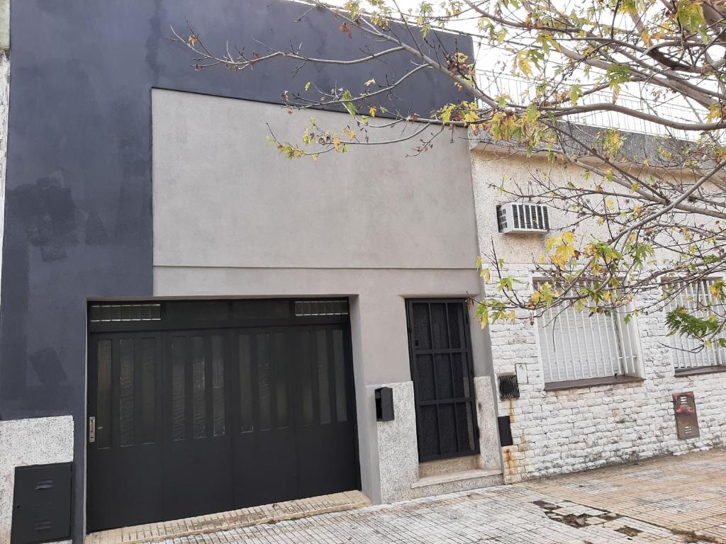 una puerta de garaje negra en un edificio blanco en Casa c/ Garage y Patio en Pergamino