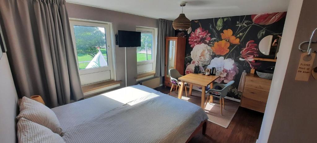 a bedroom with a bed and a table and two windows at Villa La Vida in Egmond aan Zee