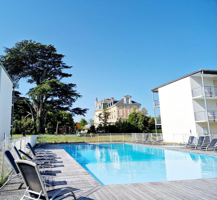 a swimming pool with lounge chairs and a building at Le Sea Breeze La Rochelle 44m2 - 2 chambres - 6 prs - Piscine in Lagord