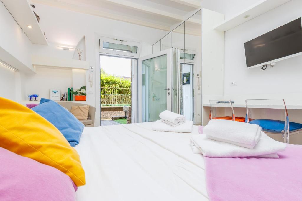 a white bedroom with a large bed with colorful pillows at FEEL - Patio del Sole in Bergamo