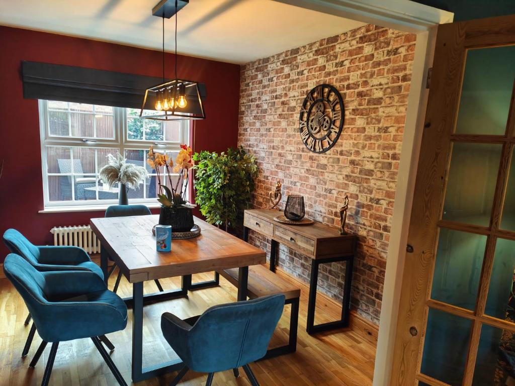 een eetkamer met een tafel en stoelen en een bakstenen muur bij Boutique Abode - With Hot Tub in Chester