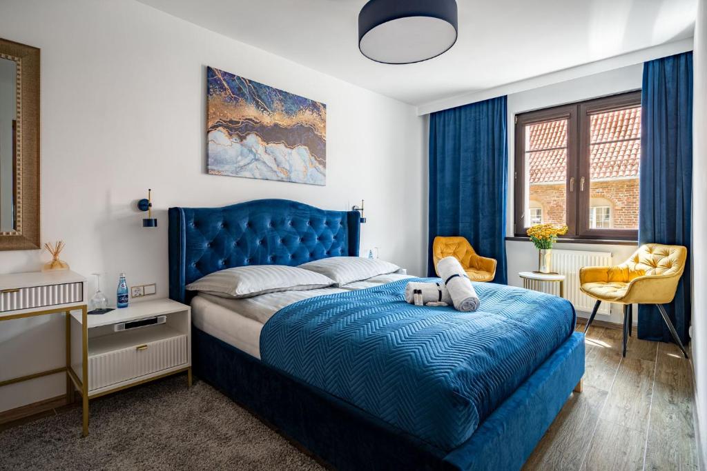 a bedroom with a blue bed with a blue headboard at Grelewicz Apartments-MyView in Toruń