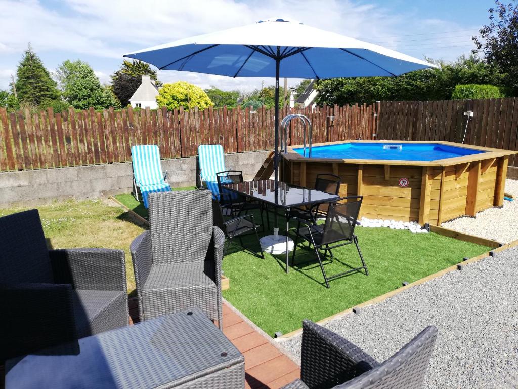 a patio with a table with an umbrella and a pool at Kerguil-hanna agréable et familiale, 4 pers, piscine privée du 15 juin à mi-septembre in Moëlan-sur-Mer