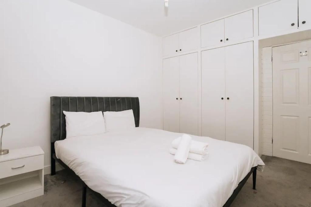 a bedroom with a large white bed with white cabinets at Sleek & Central 2BD Flat - Haymarket in Edinburgh