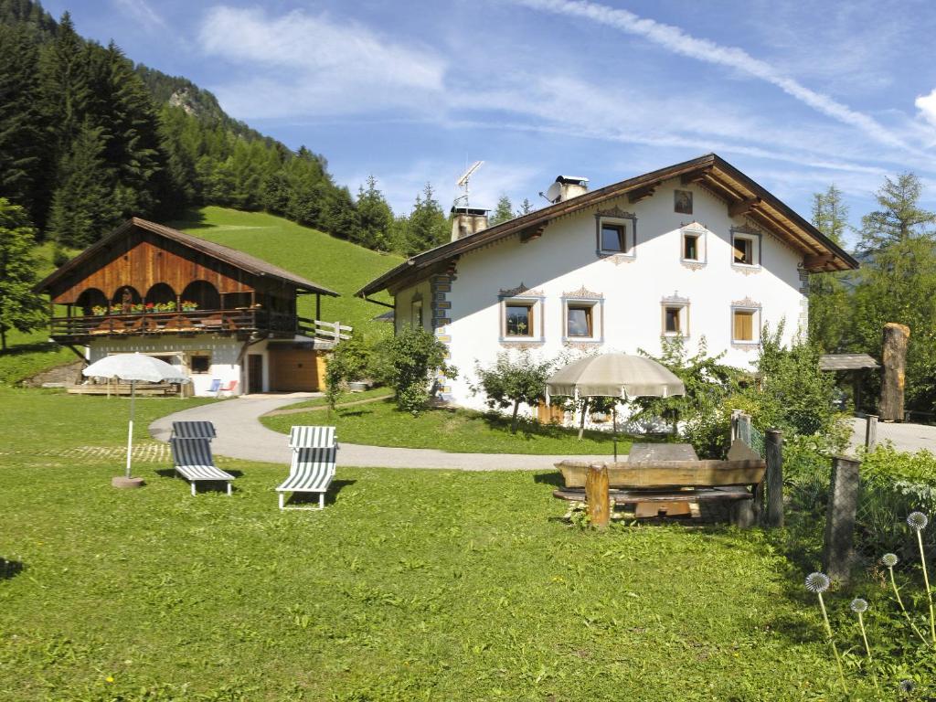 uma grande casa branca com duas cadeiras na relva em Apartment Puciacia - Bauernhof em Santa Cristina in Val Gardena