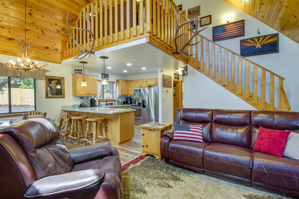 a living room with a leather couch and a staircase at Scenic Arizona Cabin Rental Near Show Low Lake! in Show Low