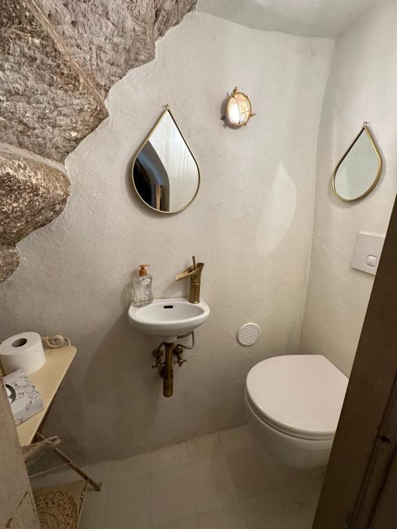 La salle de bains est pourvue de toilettes, d'un lavabo et d'un miroir. dans l'établissement DOMMO ASULETTA, à Bosa