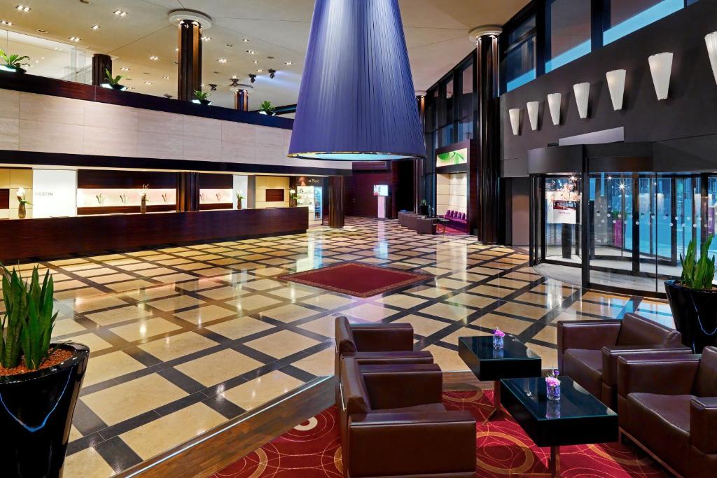 a lobby with leather chairs and a checkerboard floor at The Westin Leipzig in Leipzig