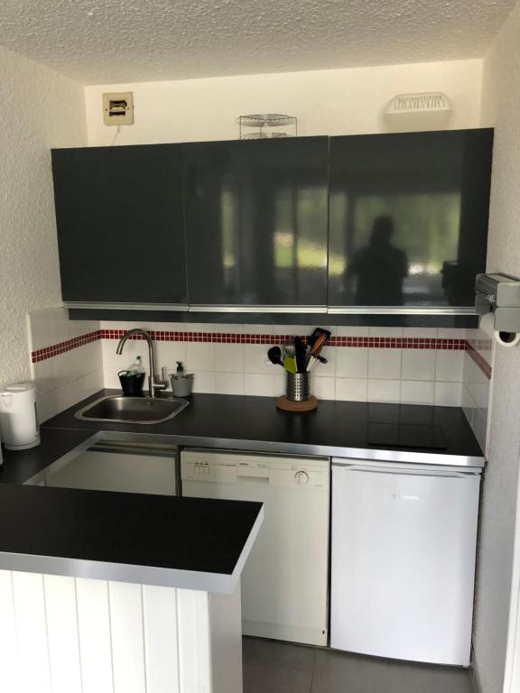 uma cozinha com armários brancos e um balcão preto em Studio à Corrençon en Vercors em Corrençon-en-Vercors