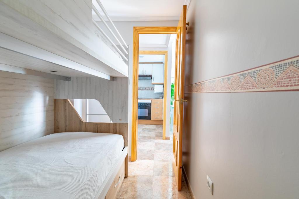 a bedroom with a bed and a door leading to a kitchen at Apartamento Pobla de farnals, vistas al mar, wifi in Puebla de Farnals