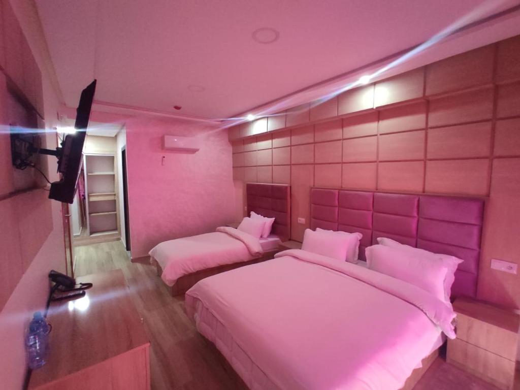 - 2 lits dans une chambre rose avec éclairage rose dans l'établissement FEKRI HOTEL, à Meknès