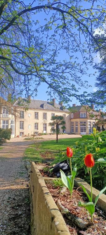 un grand bâtiment avec des fleurs rouges dans un jardin dans l'établissement Chateau de la Grand'Maison, à Bellême