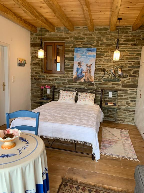ein Schlafzimmer mit einem Bett und einer Steinmauer in der Unterkunft ΠΕΤΡΙΝΟ στην Άνδρο in Agia Eleousa